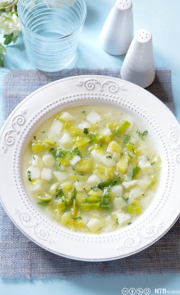 Tallerken med suppe med lysegrønne og hvite grønnsaksbiter. Foto.