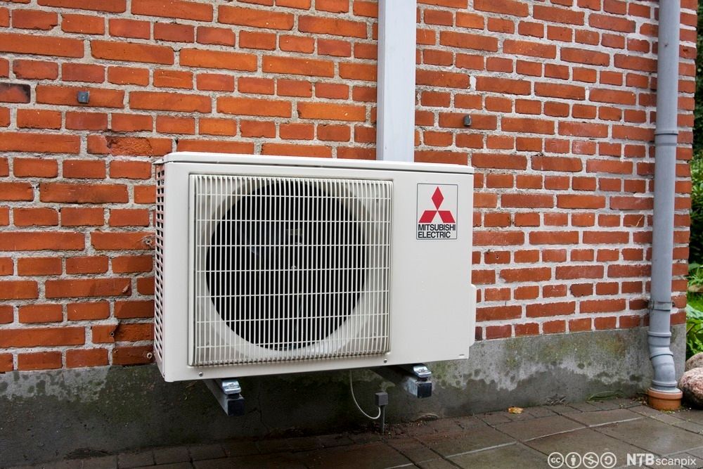 Utedelen av ei varmepumpes montert på en mursteinsvegg. Foto.