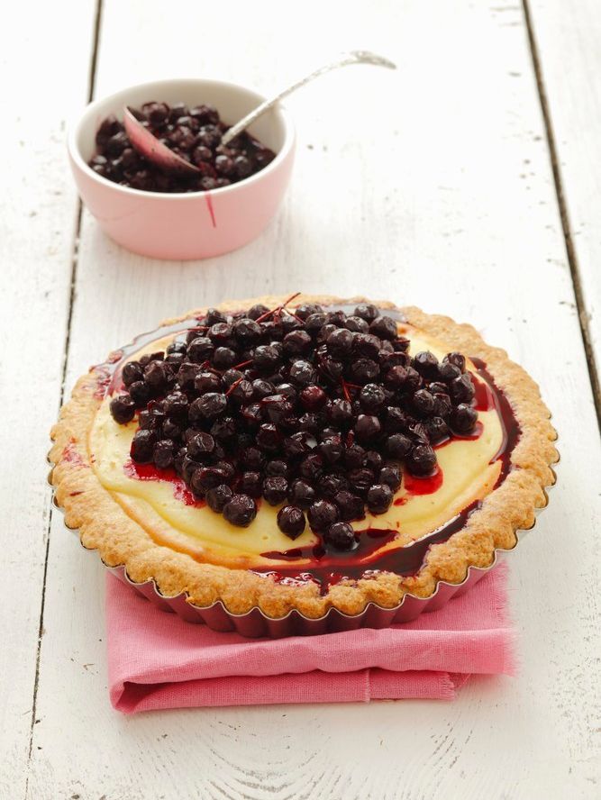 En terte fylt med vaniljekrem og en haug svarte bær. Foto.