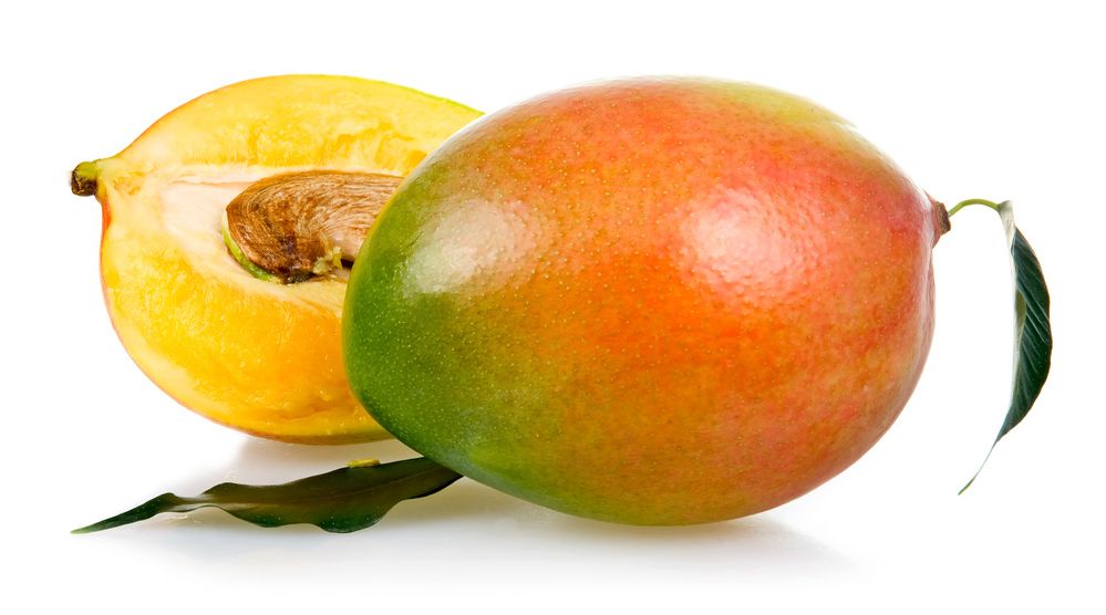 Mango delt i to mot kvit bakgrunn. Skalet har nyansar av grønt, raudt og gult. Fruktkjøttet er gult. Steinen i kjernen er synleg. Foto.