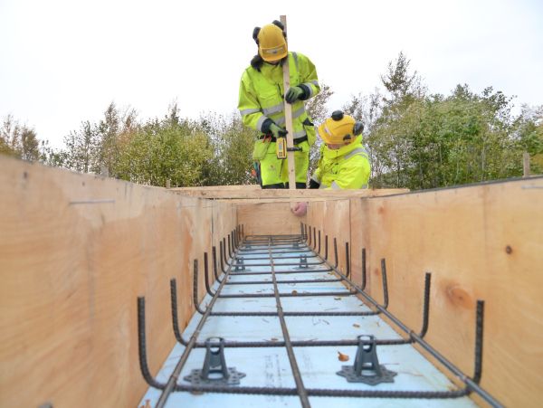 Armering i forskaling til fundament med to personar. Foto.