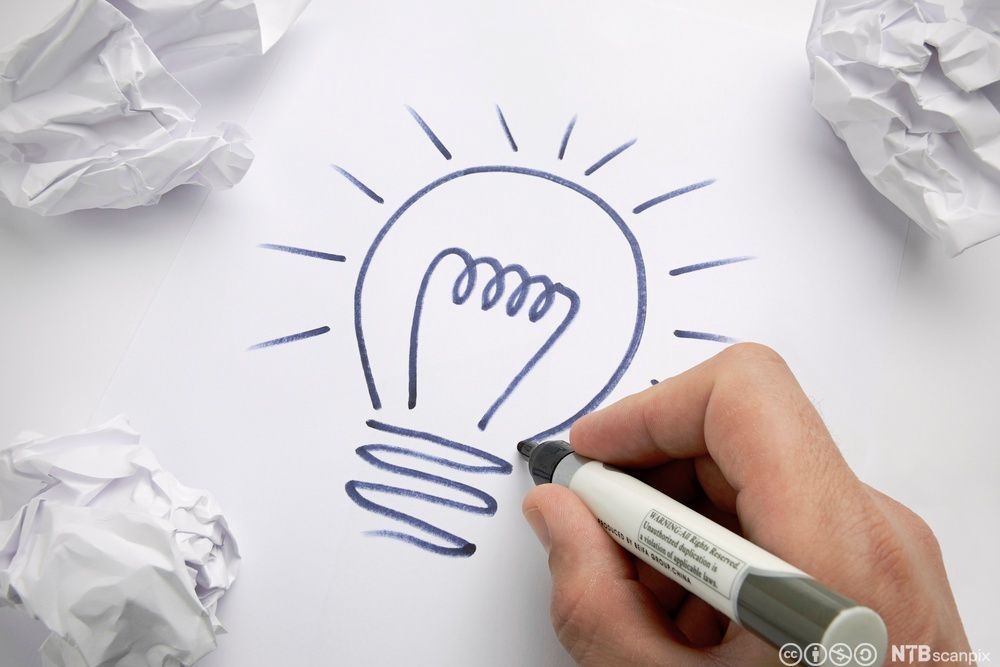 Hand som teiknar ei lyspære. Foto.