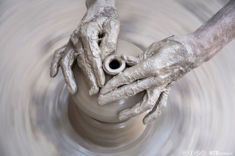 Hender lager ei krukke av leire. Foto,