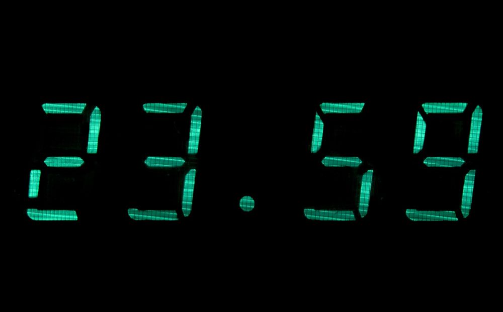 Digital klokke som viser klokkeslettet 23.59. Foto.