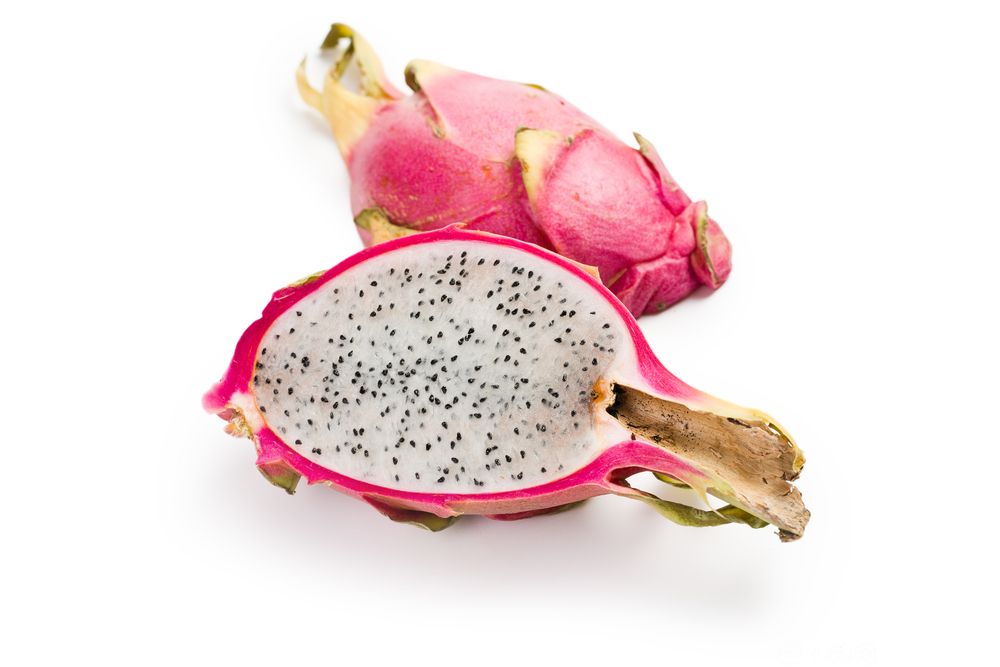 Ein hel og ein delt pitahaya frukt mot kvit bakgrunn. Foto.