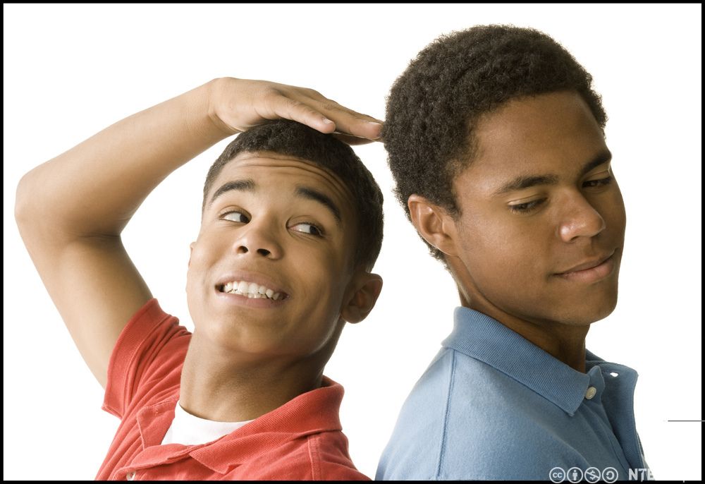 Foto av to gutar som står rygg mot rygg og samanliknar kor høge dei er.