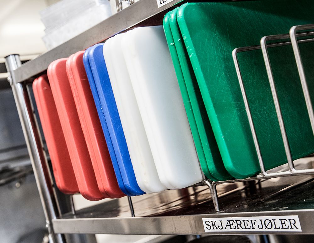 Skjærefjøler med fargekoder plassert på hylle. Foto.