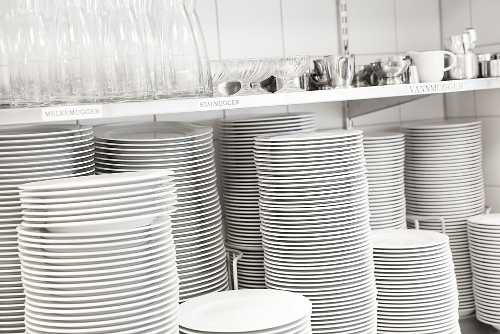 Servise og glass stablet i hyller. Foto.
