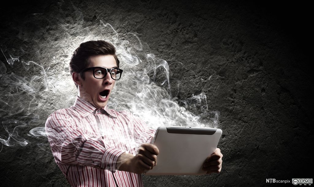 Mann rygger bakover når lys strømmer ut fra nettbrettet. Foto.