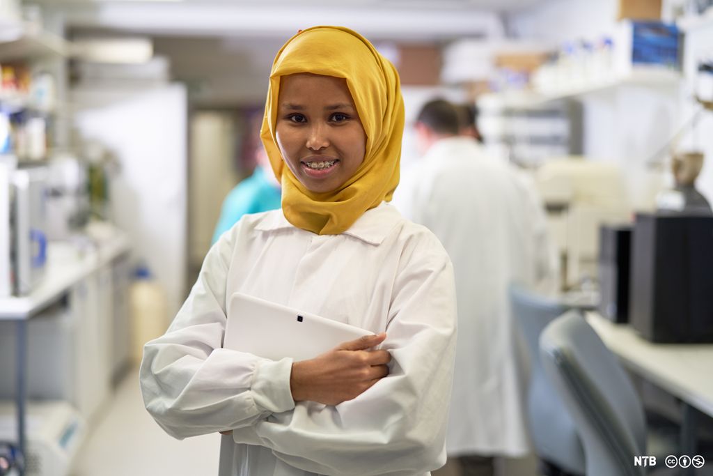 Ung forskar i labfrakk og hijab. Foto. 
