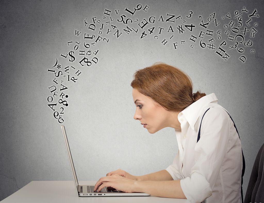 A woman is typing on her computer while letters fly around her. Photo.