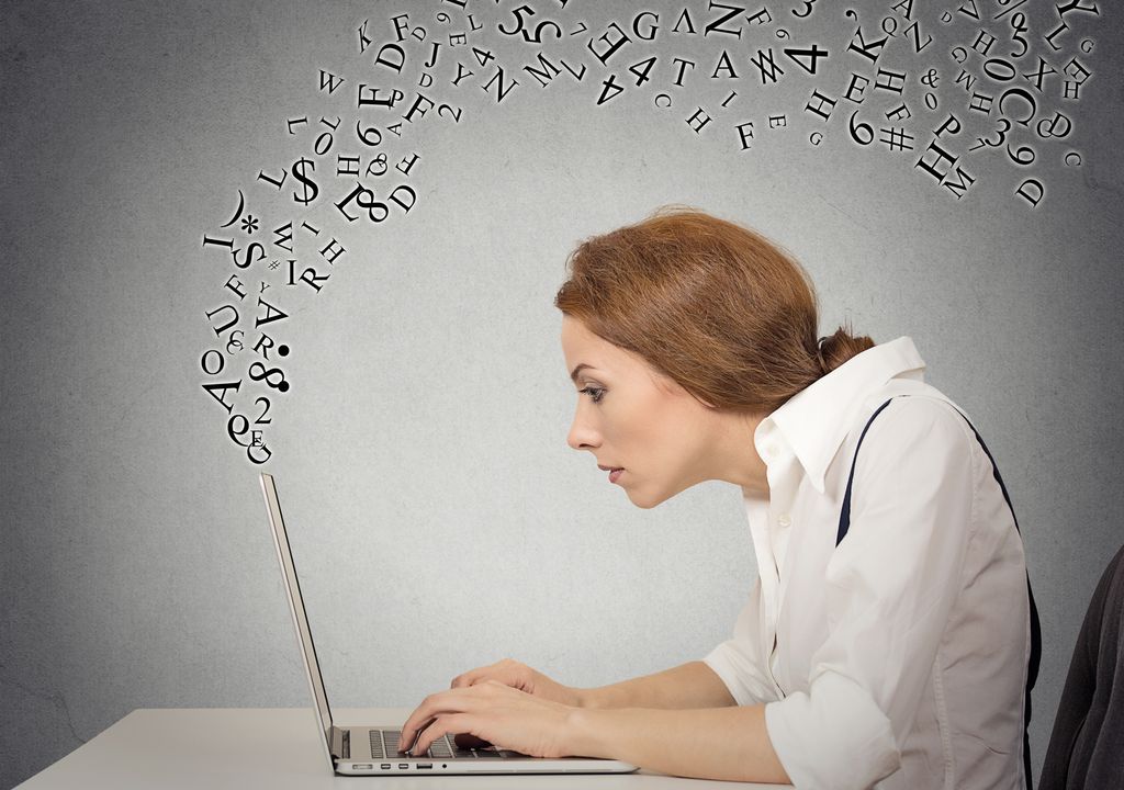 Kvinne skriver på en bærbar datamaskin. Bokstaver kommer ut av datamaskinen og svever over henne. Manipulert foto.