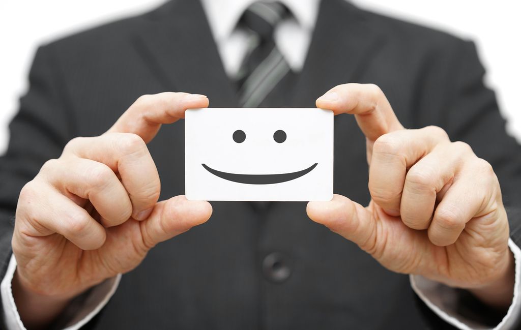 Mann som held eit kort med ein smilemunn.Foto.