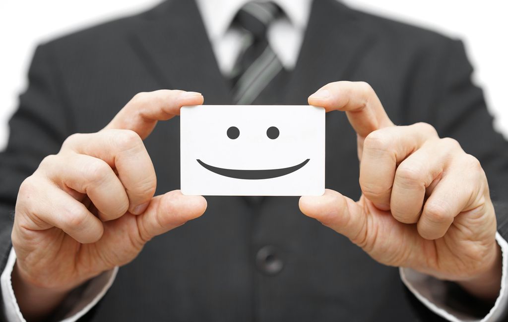 Mann som holder et kort med en smilemunn.Foto.