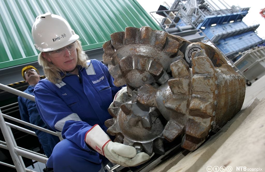 En arbeider håndterer en borkrone av typen Roller Cone. Foto.