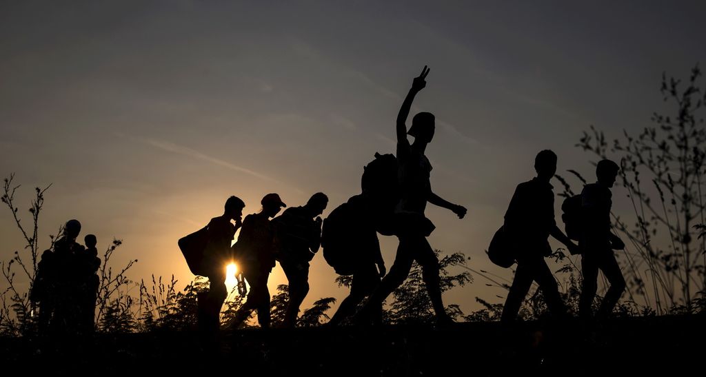 Silhouettes of 8 migrants crossing into Hungary. Photo.