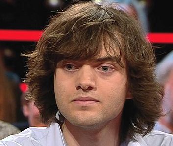 Portrait of Boyan Slat. He has shoulder length brown hair, is wearing a light blue shirt. Photo.
