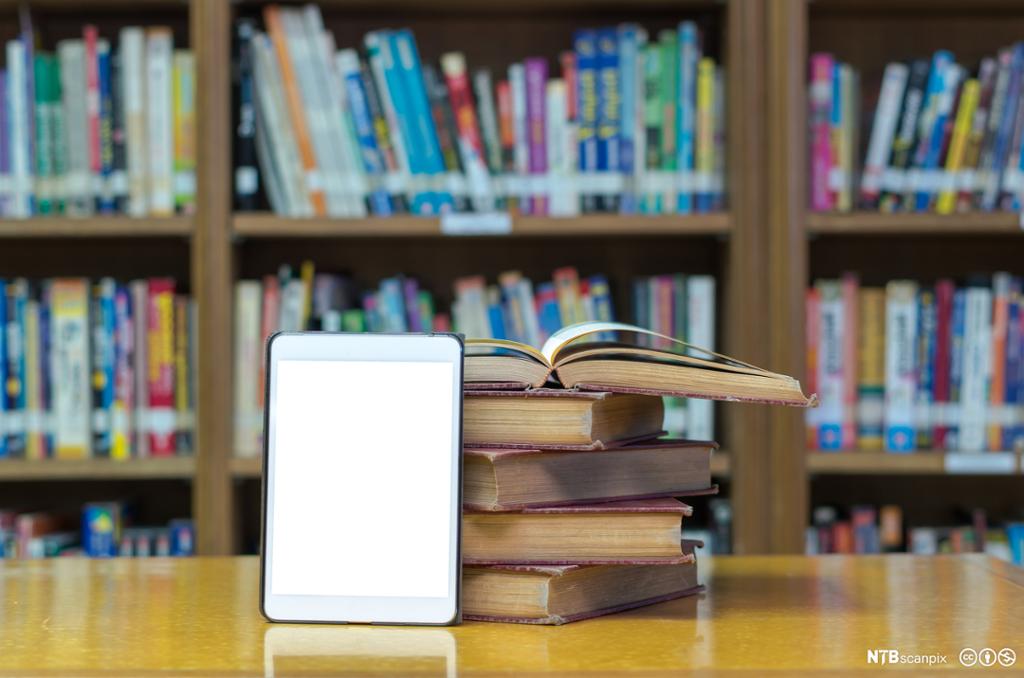 Bøker og nettbrett på et bibliotek. Bilde.