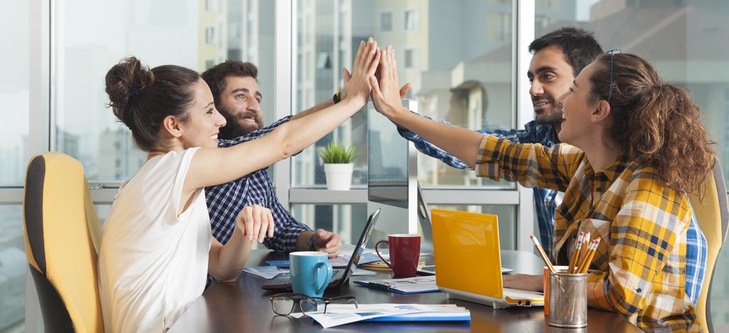 Fire personer som gir hverandre en high five. Foto.