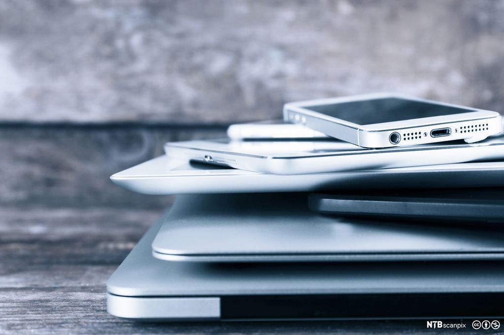 Mobiltelefon, nettbrett og pc stabla oppå kvarandre. Foto.