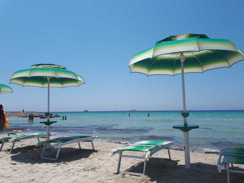 Beach chairs and parasols, sandy beach, Alghero, Sardinia. Photo.