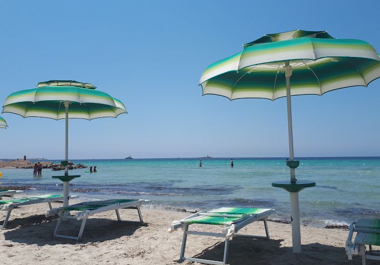 Beach chairs and parasols, sandy beach, Alghero, Sardinia. Photo.