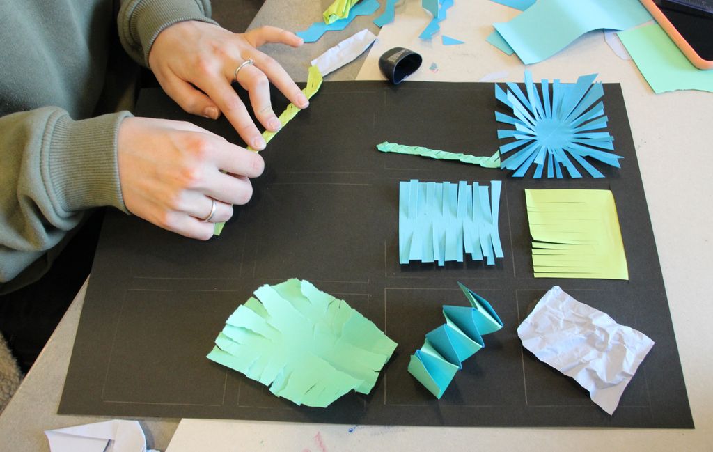 Hender som eksperimenterer med papir. Foto.