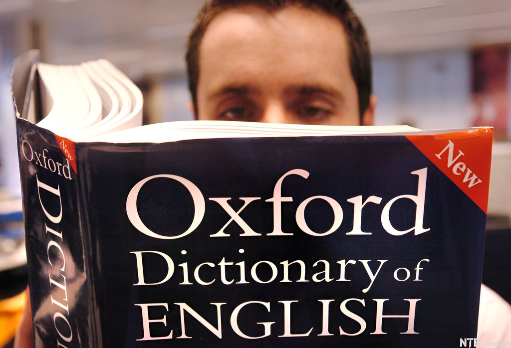 Man reading in Oxford Dictionary of English. Photo.