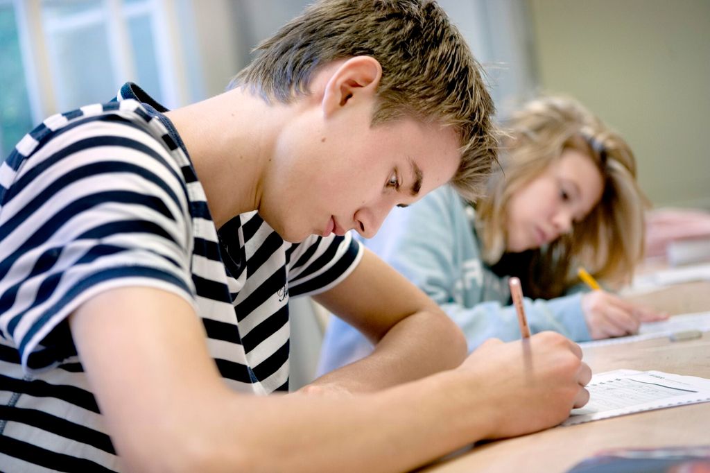 To elever som svarer på oppgaver på ark. Foto.