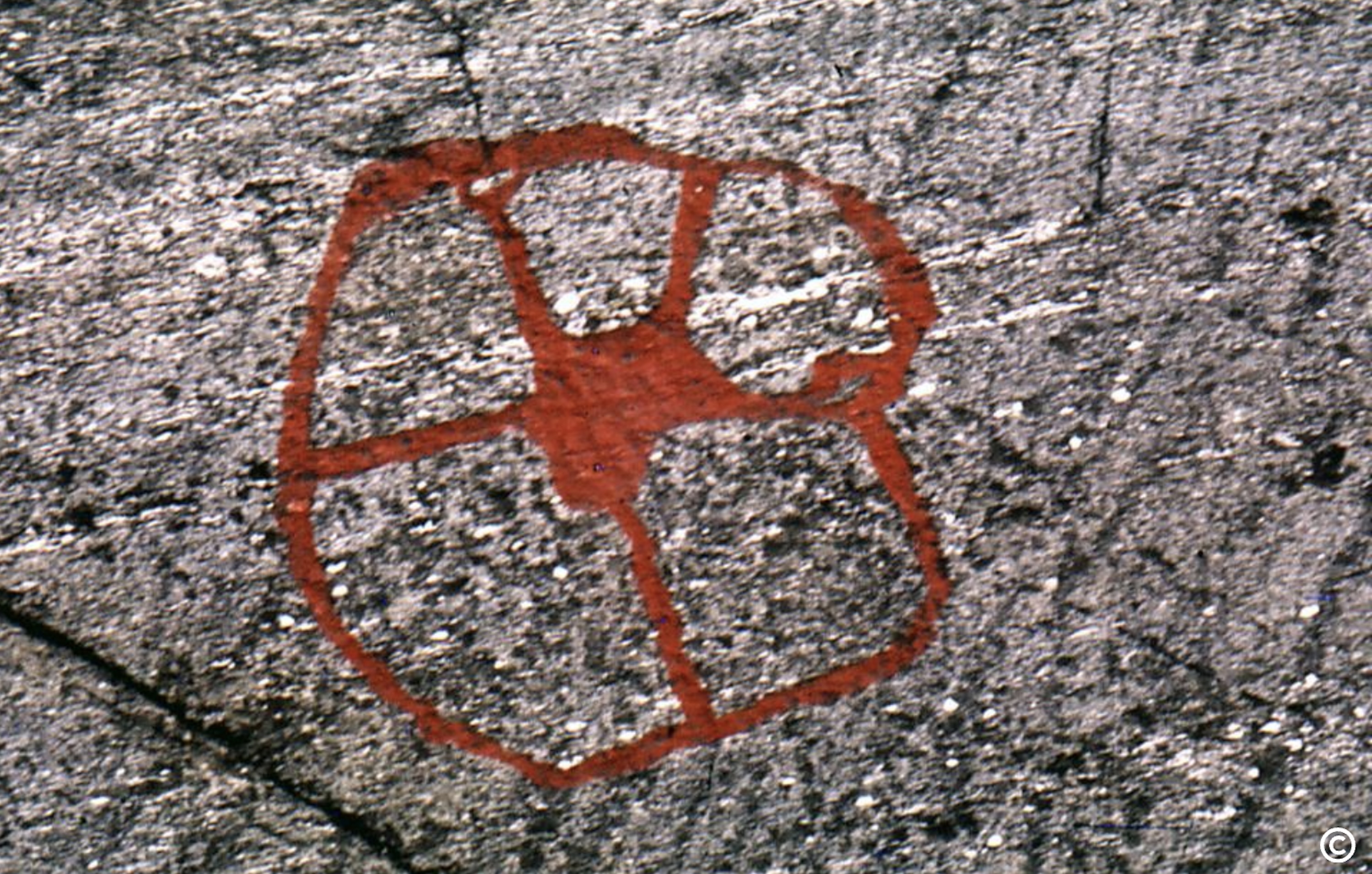 Sirkelformet helleristning med linjer ut fra senteret. Foto. 