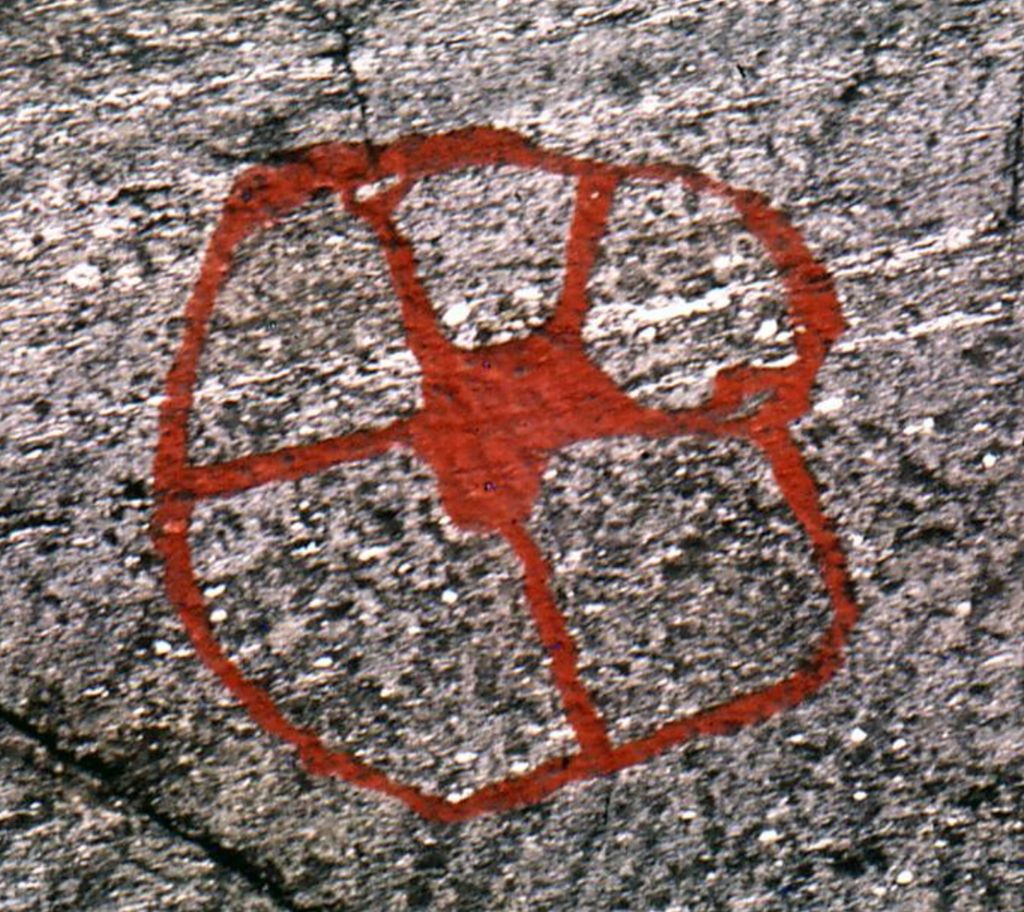Sirkelformet helleristning med linjer ut fra senteret. Foto.