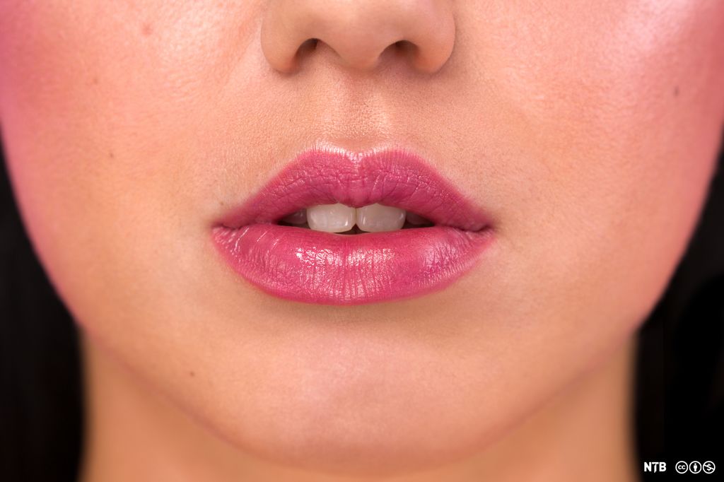 The lower half of a young woman's face. Her lips are paited and slightly parted. Photo.