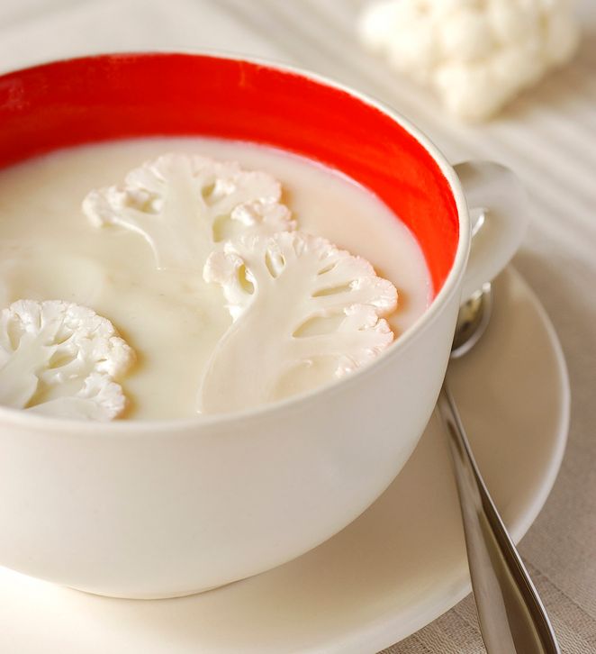 Ei skål med kvit suppe med delte blomkålbukettar i. Foto.
