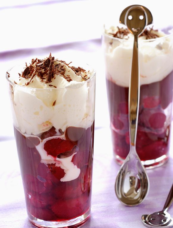 Dessertglass med kirsebær i konjakk nederst og krem på toppen. Foto.