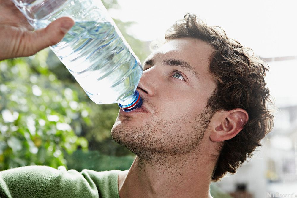 Krøllete hår, stor flaske, grønn t-skjorte.