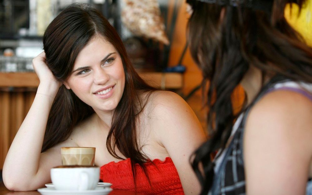 To unge kvinner drikk kaffi saman på kafé. Foto.