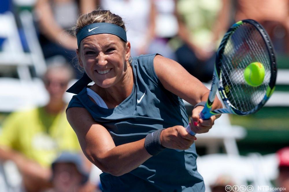 Kvinne slår ein tennisball med ein racket. Foto.