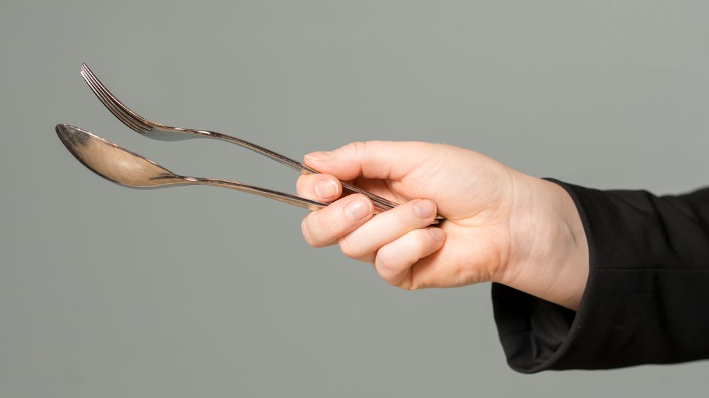 Ei hand viser korleis du skal halde ei skei og ein gaffel når du skal bruke dei som gripebestikk. Gaffelen kviler mellom tommel og peikefinger, skeia ligg mellom peikefinger og langfinger. Dei tre nedste fingrane held om enden på gripebestikket. Foto.