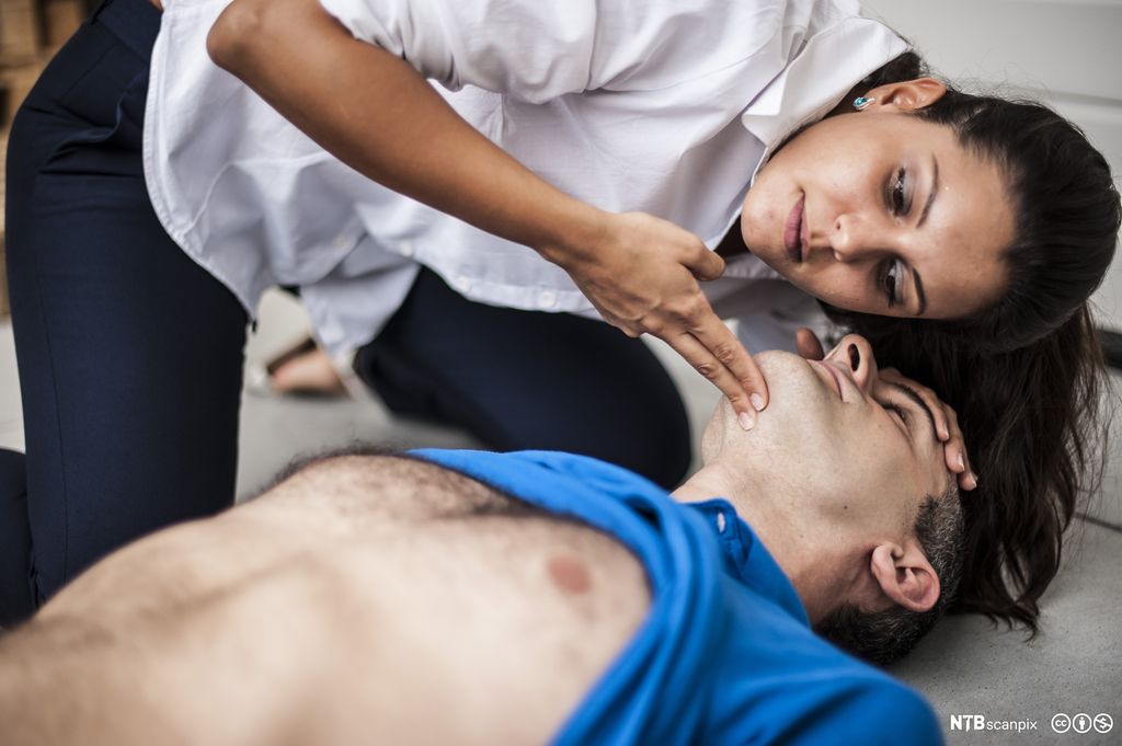 En kvinne utfører førstehjelp på en mann. Foto.