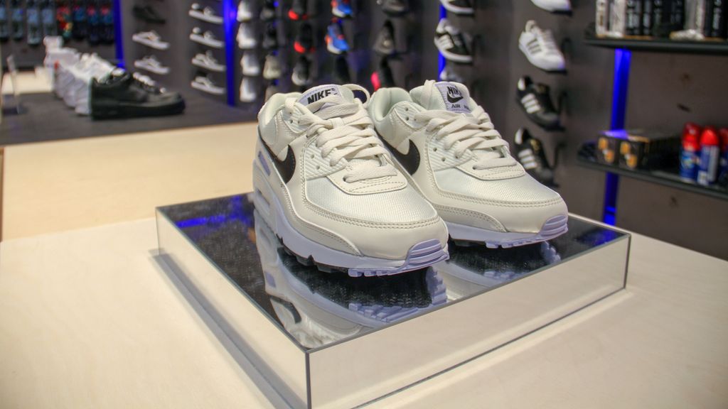 Hvite Nike-joggesko står på et speilpodium på et bord i en butikk. Foto.