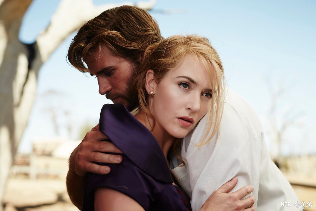 A man and a woman hugging in a dusty, desert-like landscape. Photo. 