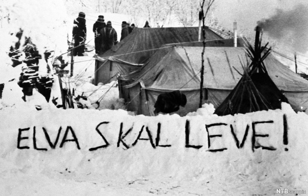 Demonstranter i telt og lavoer har skrevet «Elva skal leve!» i snøen. Foto.