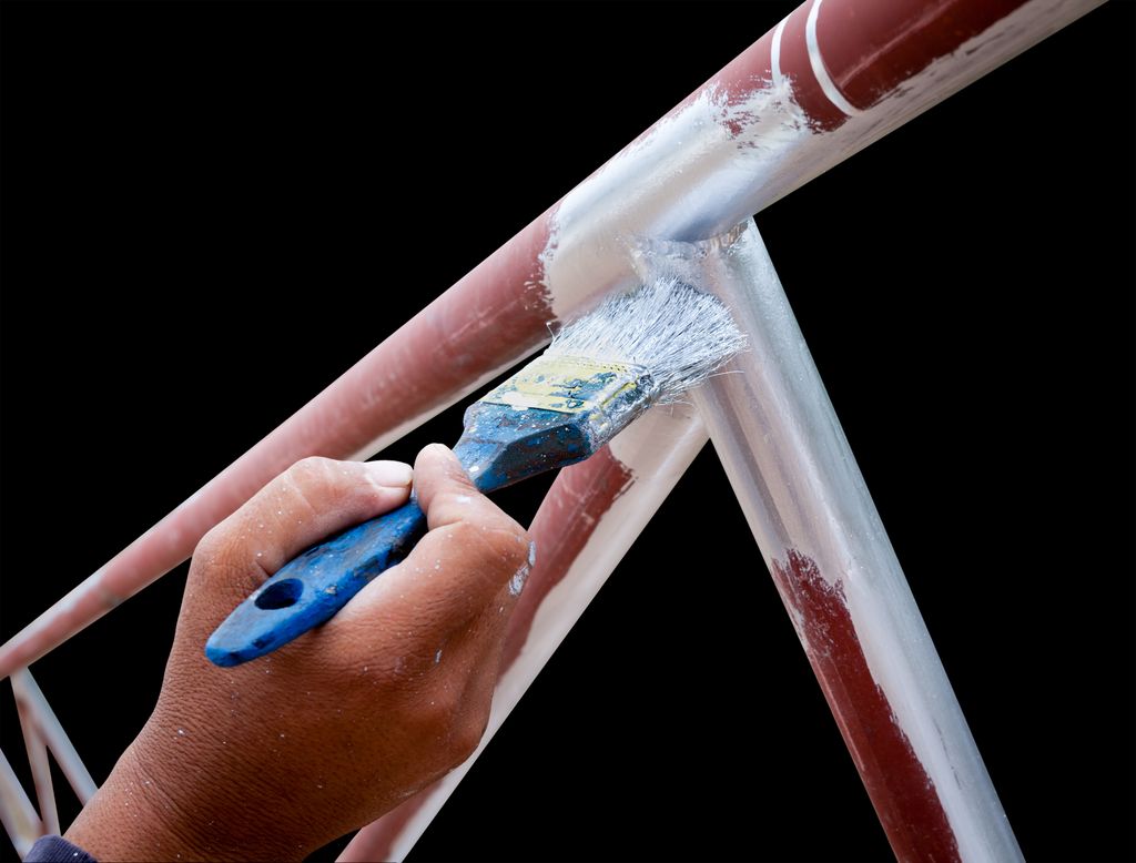 En person grunner metalldeler med pensel. Foto.