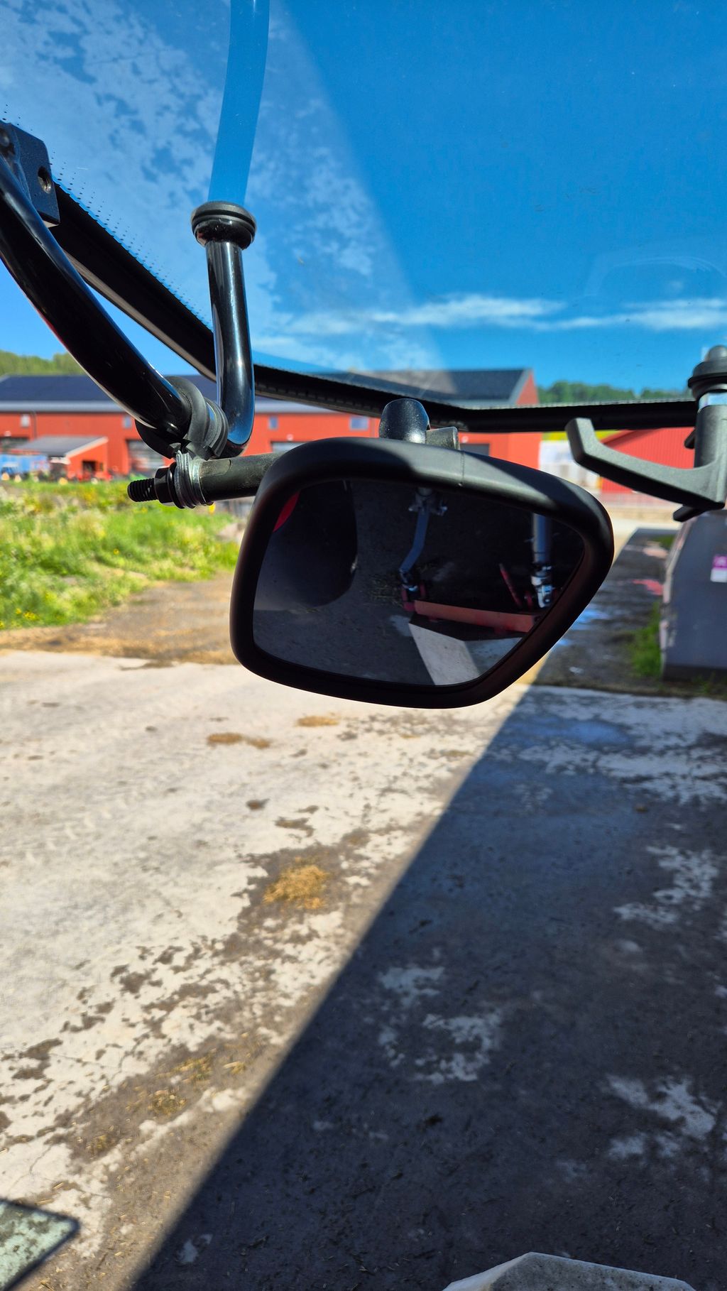 Ei open bakrute på ein traktor med ein spegel som kan vise trekkroken under kopling. Foto.