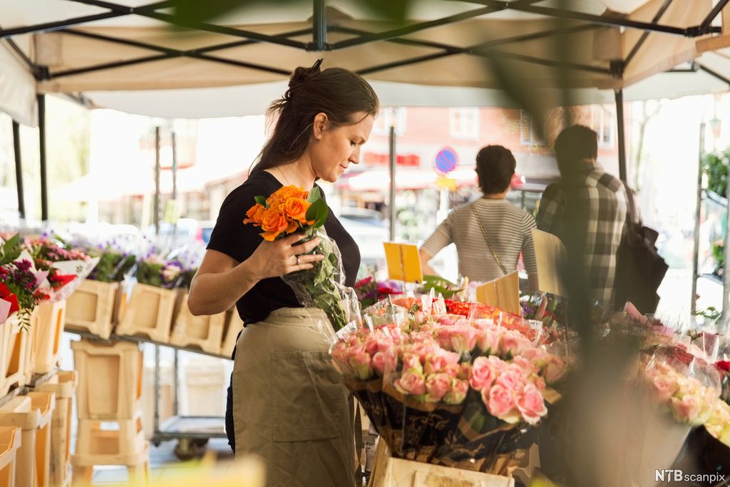 Ung kvinne setter på plass bukett med roser. Foto.