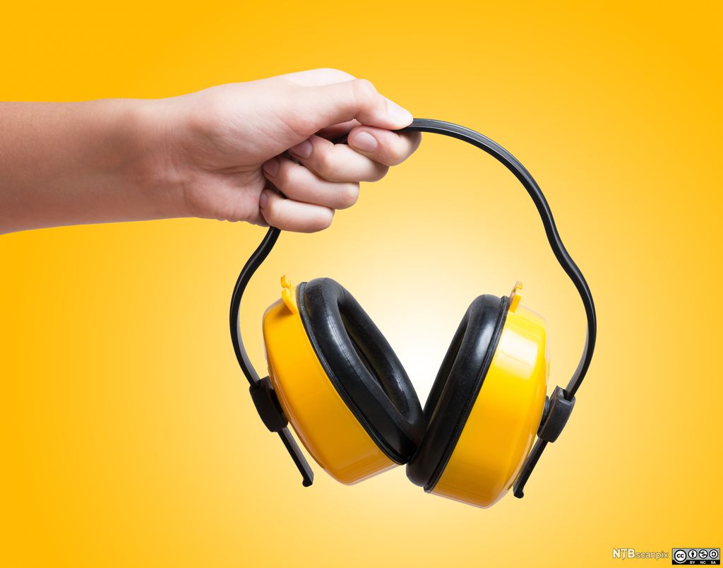 Hånd holder hørselvern. Foto.