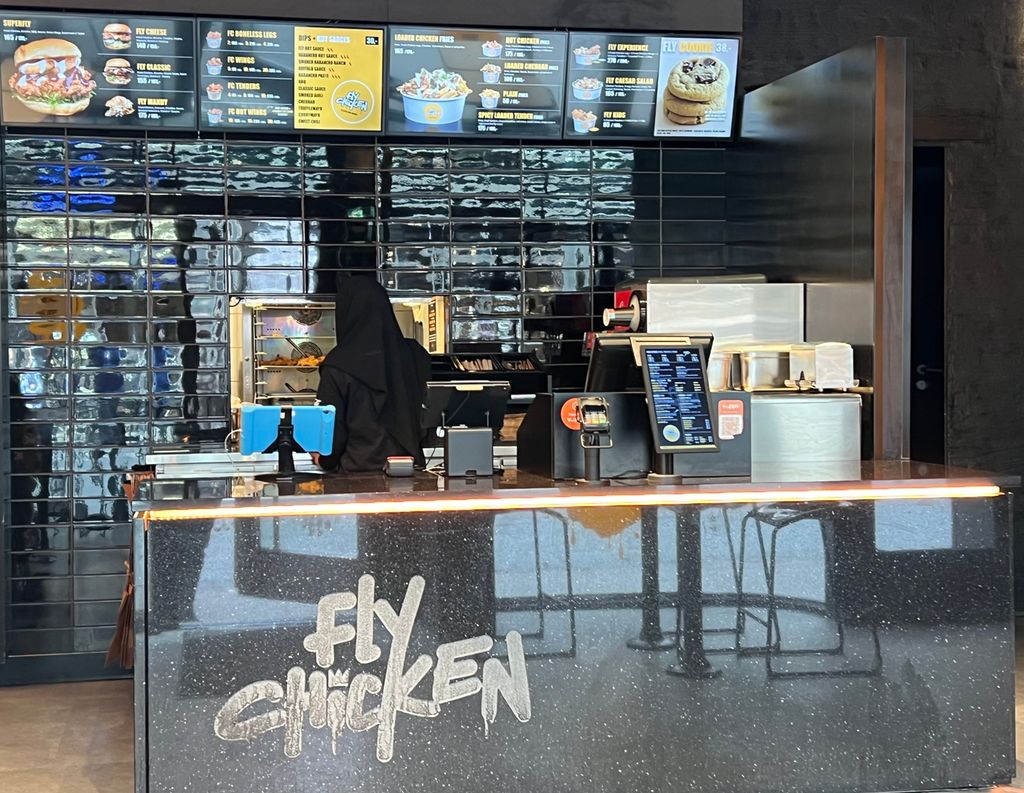 En kundedisk foran et kjøkken med hurtigmat. På disken står det Fly Chicken. Foto.