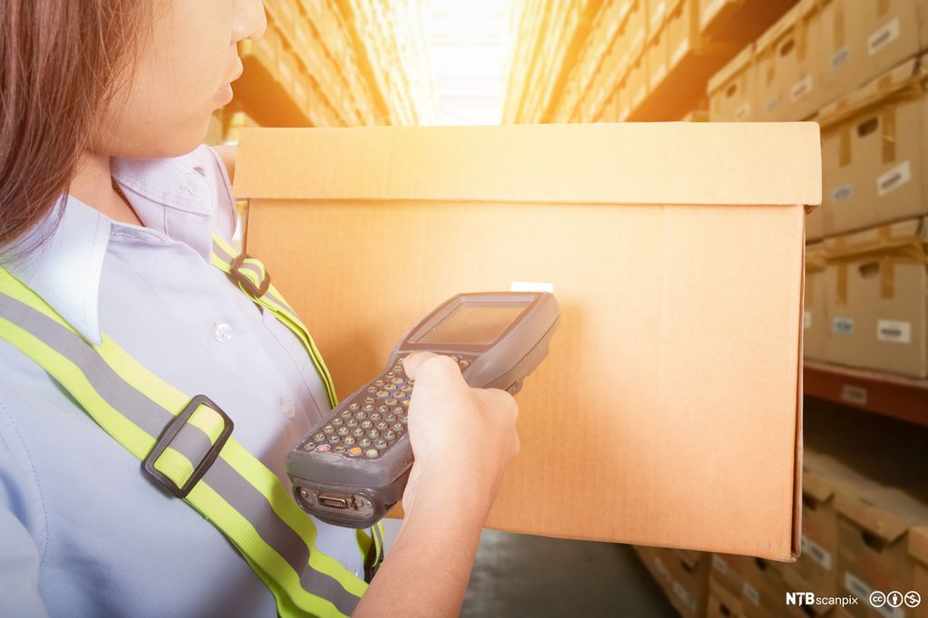 Nærbilde av person som skanner en boks med strekkodeleser. Foto.