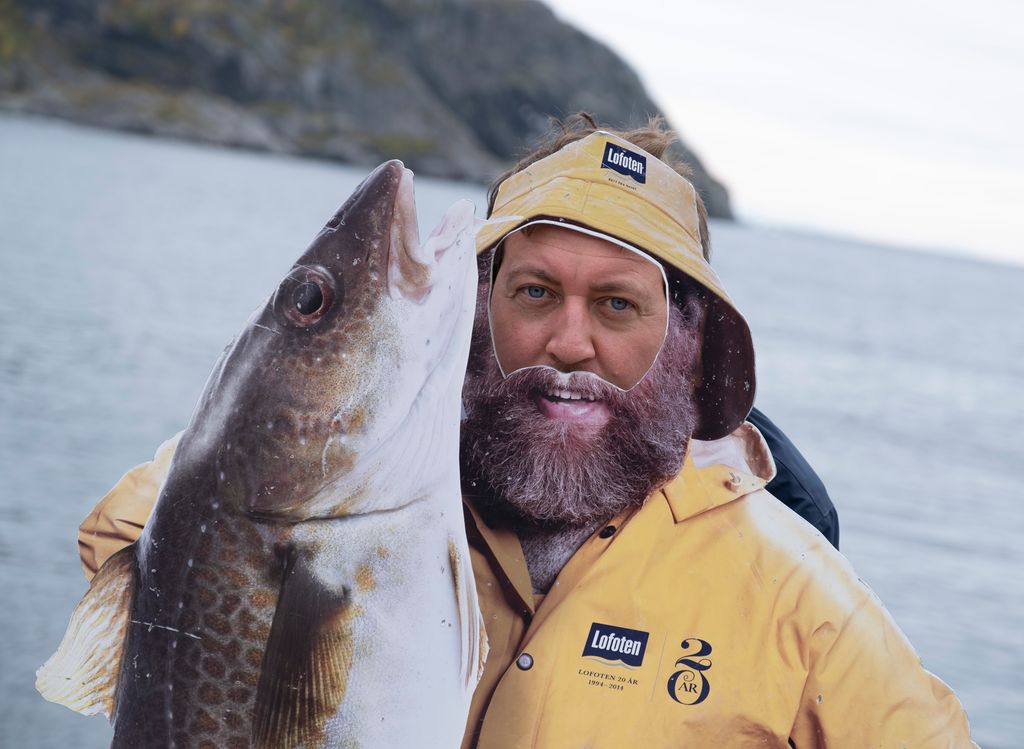 Fotoshoot, hvor du kan legge ansiktet inn i hulrommet slik at du ser ut som en fisker i gul sydvest med en diger Lofottorsk i hånda. Fotografi.
