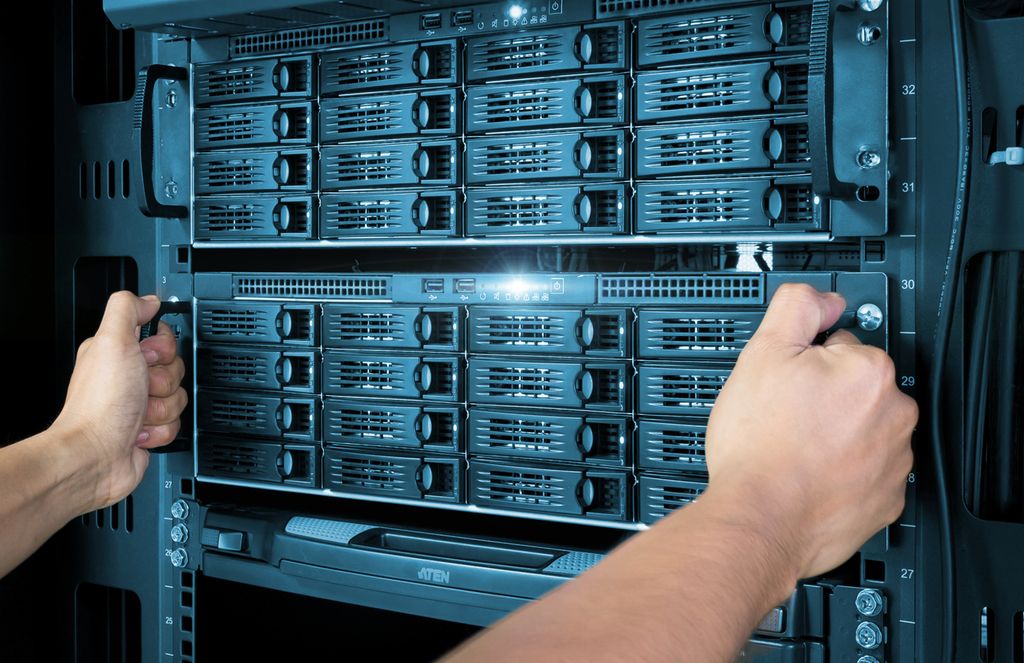 Person drar ut en lagringsserver med mange harddiskskuffer ut fra et serverskap. Foto.